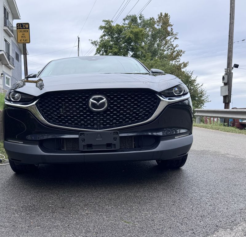 Clean black Mazda front grille and hood with a glossy reflective finish.