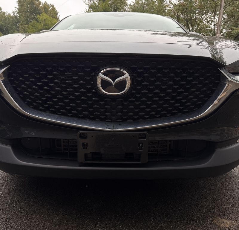 Dusty black Mazda front grille and hood with a light film of dust.