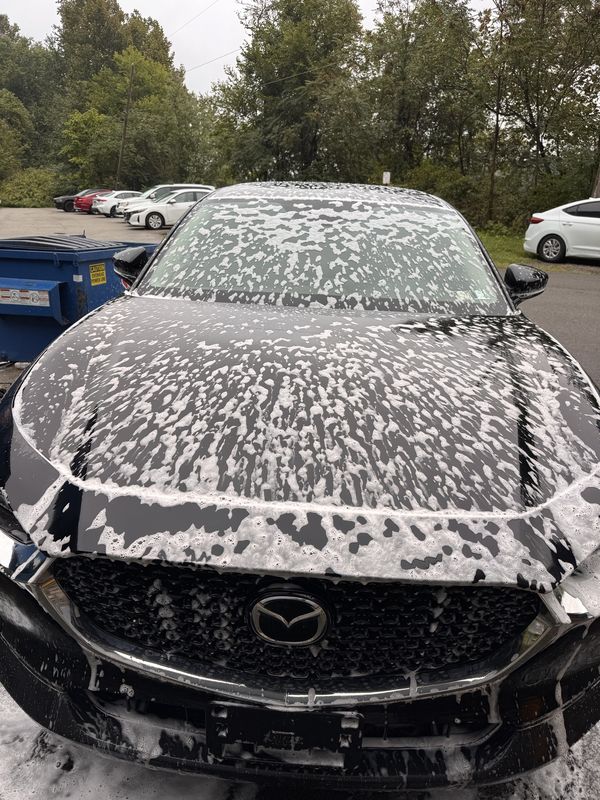 Foam wash cleaner applied to a black Mazda hood and windshield.