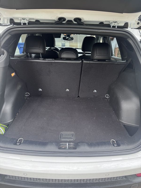Cargo area before vacuuming, with debris on the carpet.