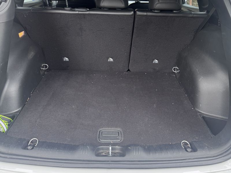 Cargo area before vacuuming, with debris across the carpet.