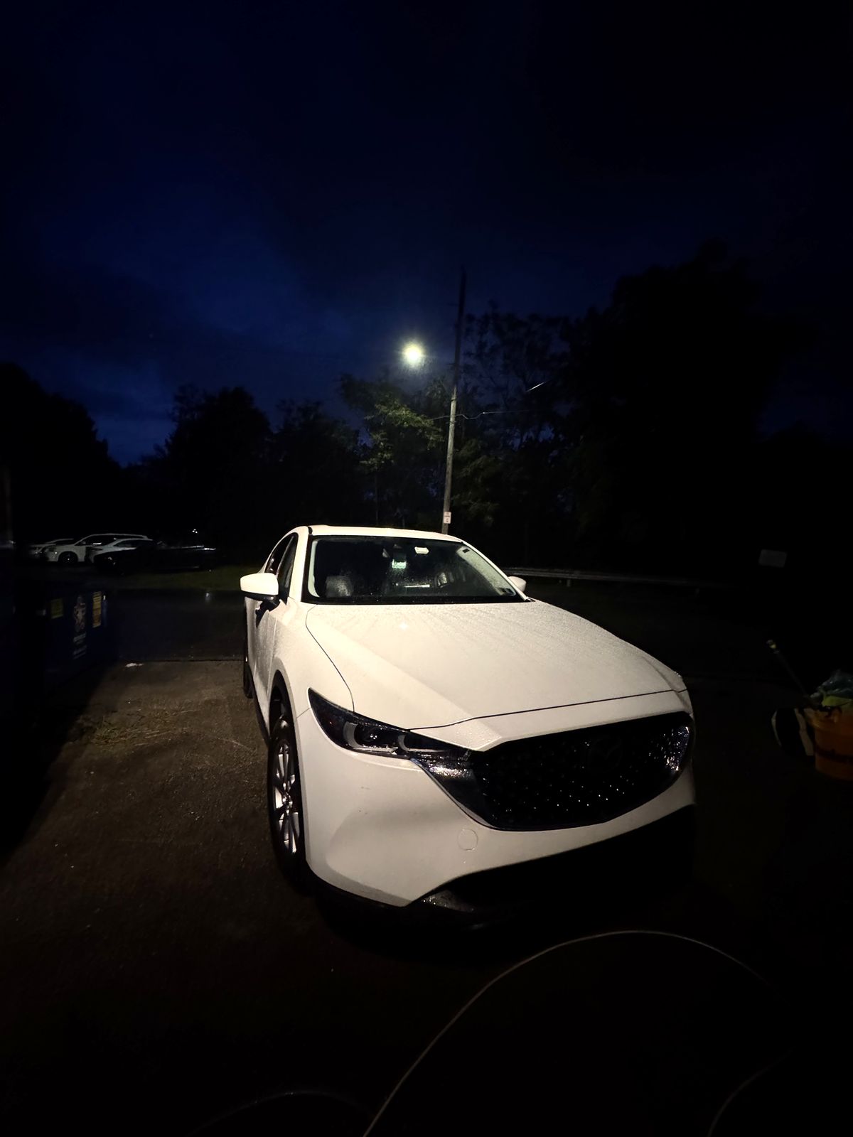 Clean white Mazda parked at night.